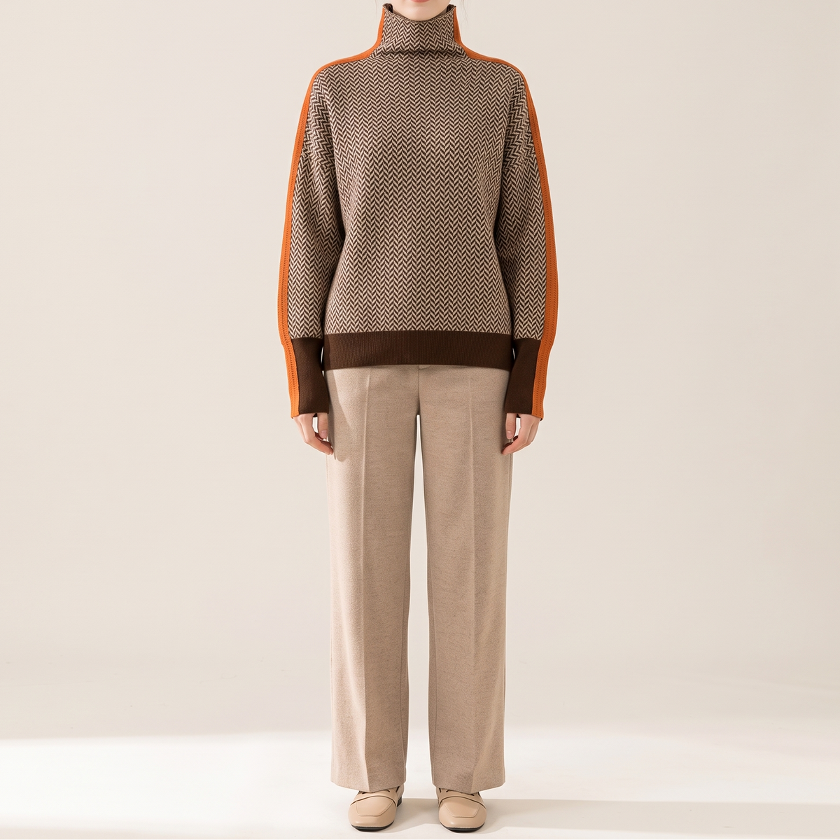 Sweter damski oversize z golfem we wzór jodełki, brązowo-kremowy z pomarańczowym pasem, na modelce, cała sylwetka