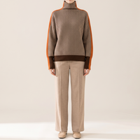 Sweter damski oversize z golfem we wzór jodełki, brązowo-kremowy z pomarańczowym pasem, na modelce, cała sylwetka