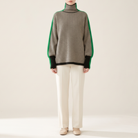 Sweter damski oversize z golfem we wzór jodełki, czarno-kremowy z zielonym pasem, na modelce, cała sylwetka